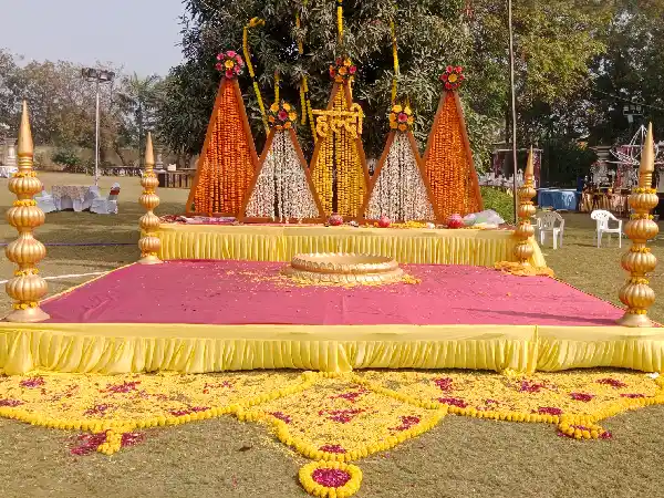 Haldi: Yellow-pink drapes; statue accents; abundant marigold and roses